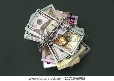 Dollars and banknotes of different countries are locked and chained in the background. Monetary crisis, financial problems, sanctions, default. The concept is the up-to-date relevant situation