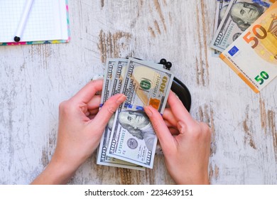 Dollars, euros, currencies of the world on the table and in a women's textile purse. Female's hands hold banknotes. The world of finance and economics. Deposits, loans, savings. Family budget planning - Shutterstock ID 2234639151