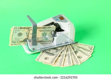 Dollars And Modern Currency Counting Machine On Green Background