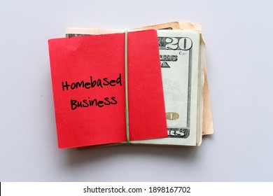 Dollars money cash in rubber band ,with red note text written HOMEBASED BUSINESS , concept of making side income or extra cash from second job from home