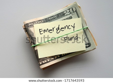 Dollars Money and paper note with text written on EMERGENCY FUND on background with copy space - concept of financial planning  saving money for purpose of rainyday crisis tough time