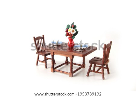 dollhouse interior - served dining table with a bowl with flowers isolated on white background. Image contains copy space