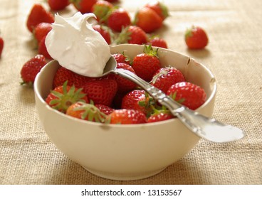 A Dollop Of Fresh Whipped Cream Rests On A Bowl Of Strawberries.