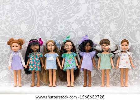 Dolls of factory mass production. Several dolls of various nationalities and racial attributes stand in a row. Children's toy. Five points of articulation. Dressed in a dress.