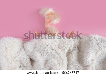 The dolls head and hands are visible from under the synthetic white fur. Minimalism concept, 80s style. Happy holidays greeting card