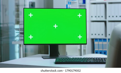 Dolly Shot Of Computer With Green Screen In Private Hospital And Personnel Wearing Uniform In The Background. PC With Blank And Copy Space Green Screen Available On Display Of Medicine Specialist In