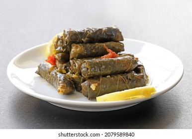 Dolma, grape leaves stuffed with rice and meat in a white plate, front view. - Powered by Shutterstock