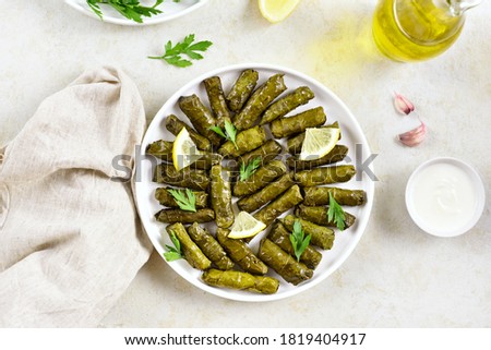 Dolma, stuffed grape leaves with rice and meat on light stone background. Top view, flat lay