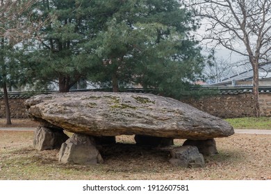Dolmen burial chamber with large boulder used as capstone on top of smaller stones in neolithic park.