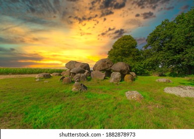 Dolmen D15 in the province of Drenthe in the Netherlands with a background of oak trees and a beautiful Dutch cloudy sky with blue spots. A dolmen is construction work from the new stone age
