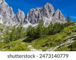 Dolomiti Alps beautiful mountain landscape. Rocky tower alpine summits in the Dolomites. Summer mountain scenic view on the hiking trekking path in the green mountain valley and blue sky with clouds