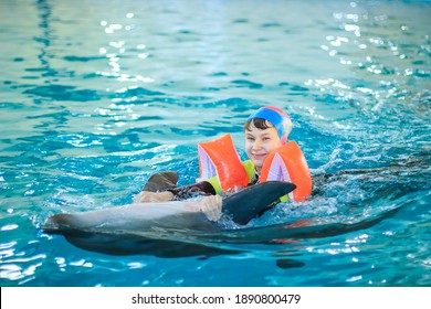 Dolphin therapy. Happy little girl swimming with dolphins in Dolphinarium. Swimming, bathing and communication with dolphins. Treatment of children by means of dolphins. Concept People and dolphins.