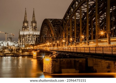 The Kölner Dom or Cologne Cathedral on the background and the Hohenzollern bridge at night.
They are the main touristic spots and landmarks of the city