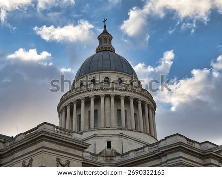 Panthéon Dome Against Dramatic Cloudy Sky - Low-angle close-up of the neoclassical Panthéon's majestic dome and column drum, capped with a cross, set against a dramatically cloudy blue sky.