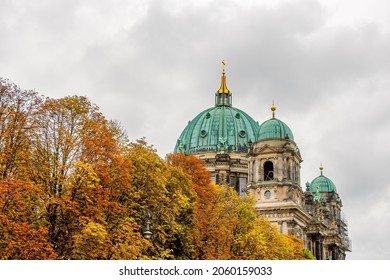 The dome of the Berlin Cathedral ( Berliner Dom ) and the colorful autumn crowns of the trees in the foreground on a cloudy day. Autumn in Berlin, Germany.
