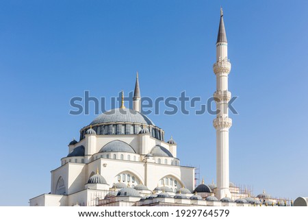 Dome and minaret of Sharjah Masjid mosque, The New Sharjah Mosque, the largest mosque in the Emirate of Sharjah, the United Arab Emirates, white sandstone facade with arched windows.