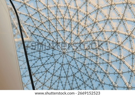 The dome showcases a complex geometric pattern formed by numerous glass panels and a supporting metal framework, creating a visually stunning and elaborate ceiling.