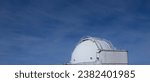 Dome of a telescope and in the background the blue sky with clouds.