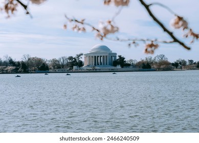 A domed, neoclassical monument seen across a body of water, framed by blooming branches. - Powered by Shutterstock