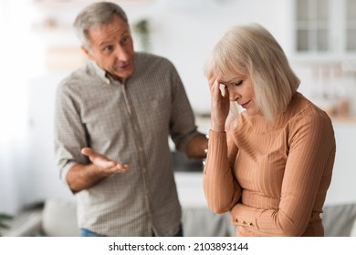 Domestic Abuse. Aggressive Senior Husband Shouting At Wife Having Quarrel Standing In Kitchen At Home. Selective Focus On Unhappy Woman. Marital Crisis And Relationship Problems Concept