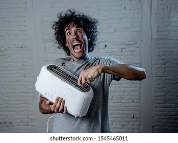 Domestic accidents and electricity danger. Young man electrocuted trying to get toast out of toaster with knife. Husband screaming as getting an electric shock with dirty burnt funny face expression.