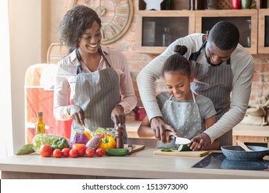 Domestic Bliss. African Dad Teaching Daughter How To Cut Vegetables, Mom Making Salad, Kitchen Interior, Free Space