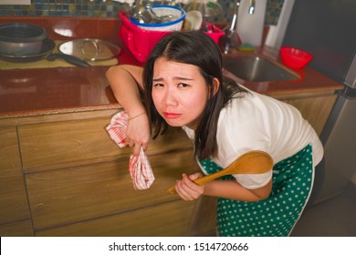 Domestic Chores Lifestyle Portrait Of Young Tired And Stressed Asian Chinese Woman In Cook Apron Working Leaning On Kitchen Sink Lazy In Moody And Upset Face Housekeeping At Home Feeling Sad