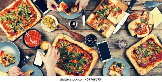 Domestic Food And Homemade Pizza. Enjoying Dinner With Friends. Top View Of Group Of People Having Dinner Together While Sitting At The Rustic Wooden Table