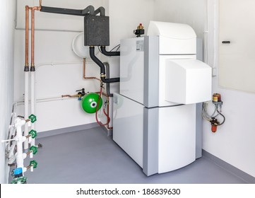 A domestic household boiler room with a new modern heating oil warm water system and pipes
