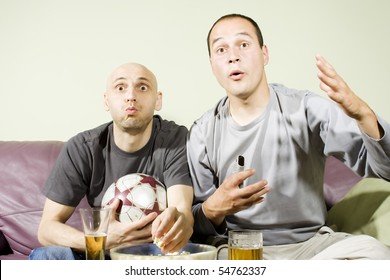 Domestic Life: Two Young Men Watching A Football Match On Tv. Sport Fans