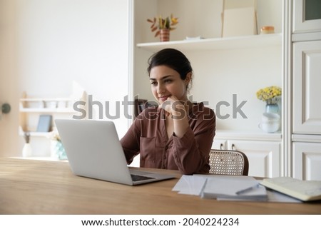 Domestic office. Positive millennial indian female freelancer work on laptop from home at morning check new messages in email client. Pensive young lady read document online think on business offer ストックフォト © 