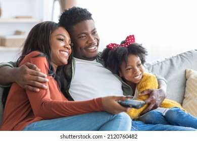 Domestic Pastime. Happy African American Family Of Three Watching Tv At Home, Young Black Parents And Cute Little Daughter Resting On Couch In Living Room, Enjoying Spending Time Together, Closeup - Shutterstock ID 2120760482