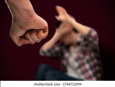 Domestic violence and abuse against women. Aggressive man with clenched fist threatening to hit scared woman. Focus on fist