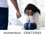 Domestic violence. African american man threatening wife with his fist, scared woman hiding face in hands, selective focus on female