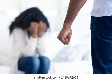 Domestic violence. African-american man threatening his girlfriend with his fist, scared woman hiding her face in hands, free space
