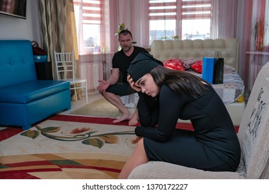 Domestic violence and the concept of family conflict. Family problems, difficulties. The unhappy, dissatisfied daughter girl sits on the sofa, her angry father scolds her. Home photography.