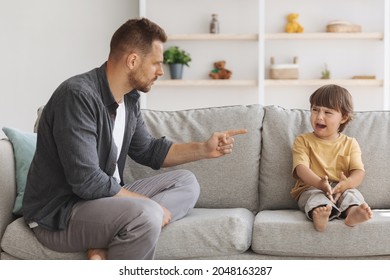 Domestic Violence And Kids Abuse. Furious Angry Daddy Shouling At His Little Son, Crying Boy Feeling Offended, Sitting On Sofa At Home