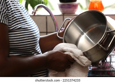 A domestic worker, Africa lady, cleaning pots and drying them - Shutterstock ID 2251374233