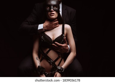dominant man strangled a submissive girl in a mask and leather belt. The concept of hard BDSM sex with domination and submission