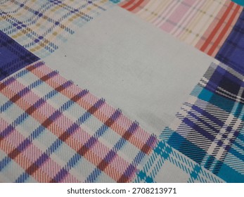 The dominant visual feature is the juxtaposition of different tartan and check patterns. In the lower-left, a vibrant plaid combines thick stripes of pink, mauve, and purple with thinner lines  nlight