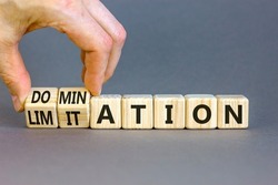 Domination Or Limitation Symbol. Businessman Turns Cubes, Changes The Word Domination To Limitation. Beautiful Grey Table, Grey Background, Copy Space. Business, Domination Or Limitation Concept.