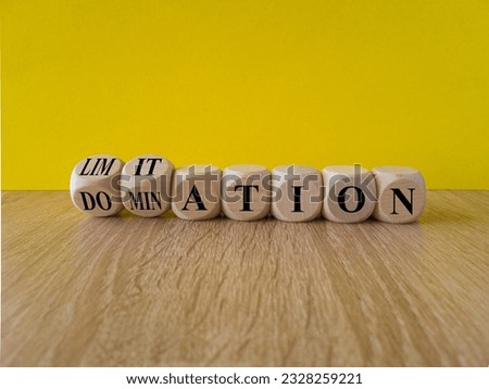 Domination or limitation symbol. Turned cubes, changes the word domination to limitation. Beautiful wooden table, yellow background, copy space. Business, domination or limitation concept.