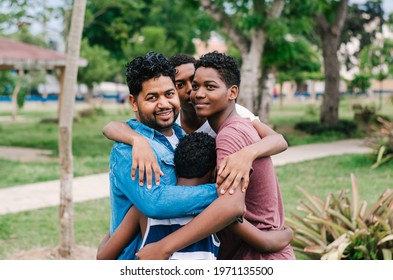 Dominican Latino origin man celebrating father's day with his children in the park, dark-skinned family having fun, children hugging their father