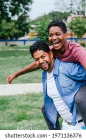 Dominican Latino Origin Man Celebrating Father's Day With His Children In The Park, Dark-skinned Family Having Fun, Father Carrying His Son