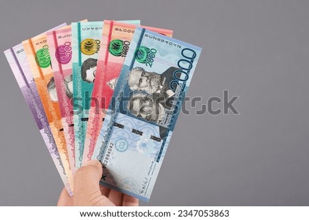 Dominican money - peso in the hand on a gray background