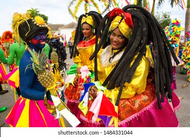 Dominican Republic, Punta Cana - March 3, 2018: People In Colorful Themed Costumes At A Carnival. Faces Painted With National Colors. Girls In Colored Costumes At The Festival