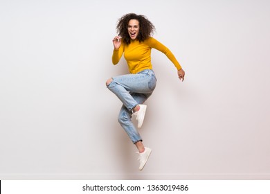 Dominican Woman With Curly Hair Jumping Over Isolated White Background