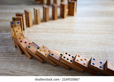 Domino effect concept with wooden dominoes pieces row falling on wooden background. Business crisis management, finance intervention, conflict prevention or mistake consequence concept