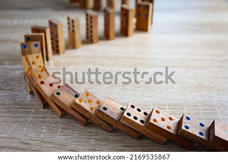 Domino effect concept with wooden dominoes pieces row falling on wooden background. Business crisis management, finance intervention, conflict prevention or mistake consequence concept