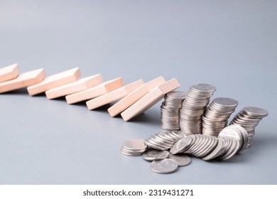 Domino effect impacts some of the heap of coins falling down, losing money, finance status, investment in domino effect concept